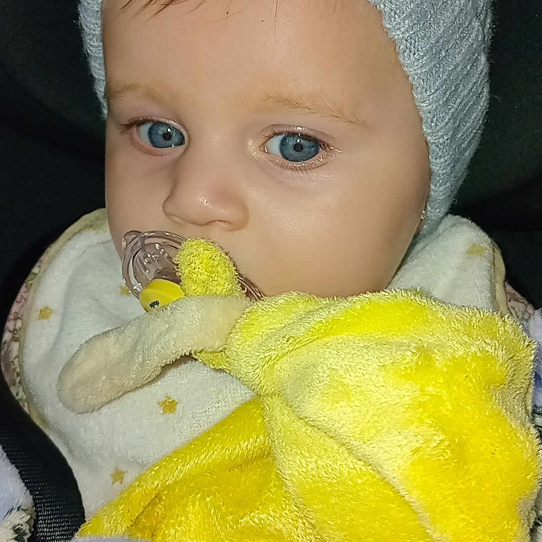 Christine Santiago participe au concours pour gagner de l'argent avec cette photo : baby, blanket, blue_eyes, child, close_up, clothing, comfort, cozy, cute, hat, indoor, infant, knitted_hat, pacifier, plush_toy, portrait, sleepy, soft_texture, warm, yellow