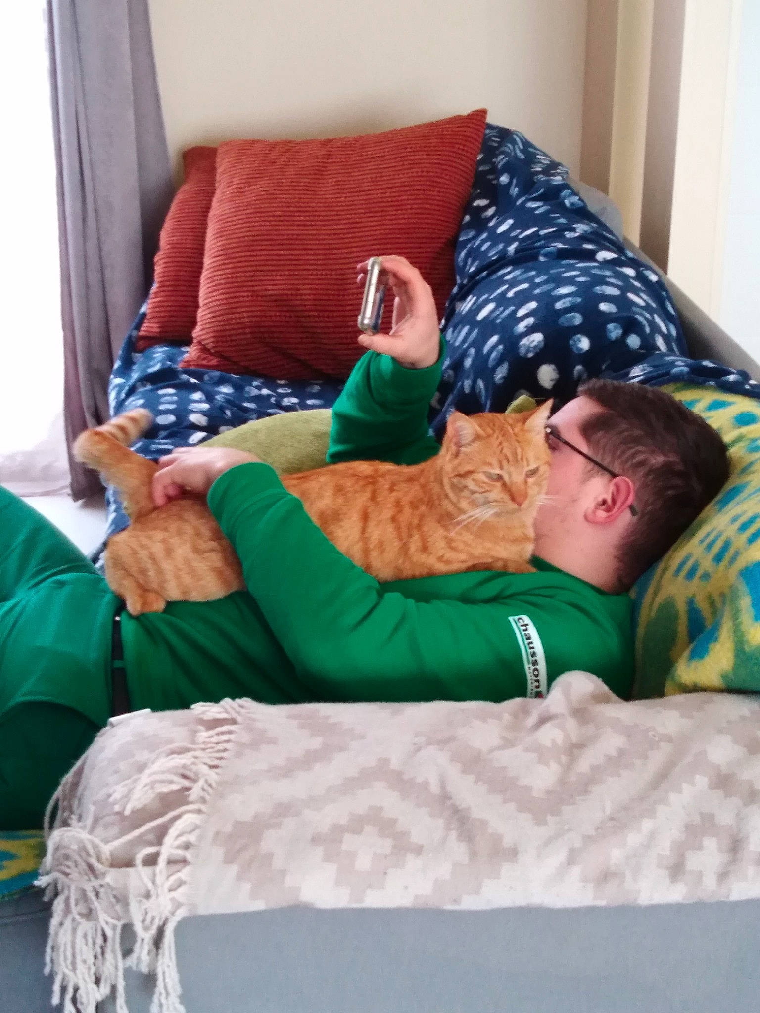 Pablo participe au concours pour gagner de l'argent avec cette photo : azure, bedding, comfort, couch, event, flooring, furniture, green, human_body, human_leg, interior_design, knee, leisure, linens, room, t_shirt, thigh, throw_pillow, wood, wrist