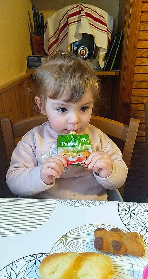 Noéline participe au concours pour gagner de l'argent avec cette photo : baby, baby_toddler_clothing, biting, chair, cheek, child, comfort_food, dress, eating, flooring, fun, hair, happy, person, picture_frame, play, room, sitting, sweetness, toddler