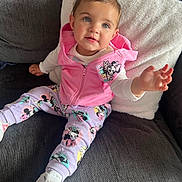 Amelia-Rose is registered to the contest to win money with this photo: toddler, child, pink_hoodie, minnie_mouse, purple_bow, white_pillow, gray_couch, sneakers, reaching_hand, cute, indoor, smiling, fashion, casual_wear, happy, portrait, seated, cozy, playful, baby