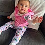 toddler, child, pink_hoodie, minnie_mouse, purple_bow, white_pillow, gray_couch, sneakers, reaching_hand, cute, indoor, smiling, fashion, casual_wear, happy, portrait, seated, cozy, playful, baby