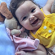 Luna participe au concours pour gagner de l'argent avec cette photo : baby, child, smile, happy, plush_toy, blanket, yellow_clothing, curly_hair, cute, infant, closeup, face, hand, lying_down, soft_toy, comfort, indoors, skin, expression, adorable