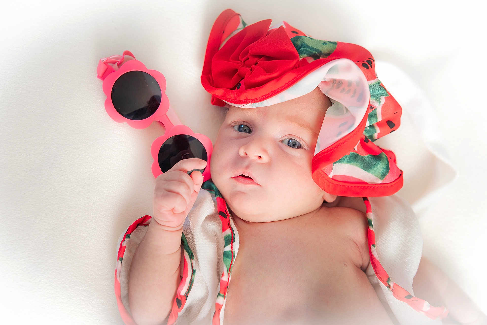 Mila participe au concours pour gagner de l'argent avec cette photo : baby, child, infant, sunglasses, pink, hat, flower_shaped, colorful, white_background, soft_lighting, portrait, cute, hand, face, blue_eyes, summer, accessory, fashion, closeup, skin