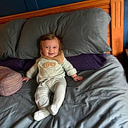 Roman is registered to the contest to win money with this photo: baby, bed, pajamas, smile, happy, child, pillow, blanket, wood, headboard, indoors, person, sleepwear, comfort, rest, furniture, cute, infant, cozy, relaxation