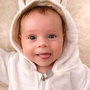 Atlas is registered to the contest to win money with this photo: baby, child, hoodie, bunny_ears, tongue_out, cute, infant, smiling, face, portrait, soft_background, white_clothing, playful, close_up, young_child, warm_tone, happy, expression, indoor, adorable