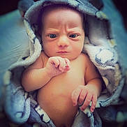 Elliott is registered to the contest to win money with this photo: baby, infant, blanket, wrapped, serious_face, skin, hand, fingers, newborn, portrait, cute, soft_texture, indoors, young_child, expression, human, sleepwear, cozy, lying_down, closeup