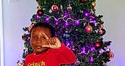 Devon joined the competition — help win amazing prizes! child, toddler, christmas_tree, christmas, holiday, ornaments, lights, star, grinch, pajamas, red_slippers, smiling, salute, standing, indoor, home, festive, portrait, decorations, tree_skirt