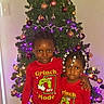 Devon is registered to the contest to win money with this photo: children, siblings, christmas, christmas_tree, grinch, pajamas, matching_outfits, holiday, ornaments, lights, presents, indoors, portrait, standing, smiling, girl, boy, braids, carpet, festive_decorations