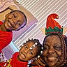 Devon is registered to the contest to win money with this photo: children, adult, family, selfie, smiling, portrait, christmas, holiday, elf_hat, red_clothing, bedroom, pillows, window_blinds, braids, beaded_hair, happy, indoor, close_up, festive, people