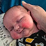 baby, infant, sleeping, hand, rosy_cheeks, pillow, blue_background, onesie, patterned_clothing, cute, peaceful, resting, child, portrait, indoor, soft_light, newborn, person, smiling_eggs, toast