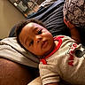 baby, child, infant, portrait, face, lying_down, couch, pillow, indoor, home, clothing, shirt, mickey_mouse, cartoon, black_hair, brown_skin, looking_at_camera, relaxed, close_up, photography