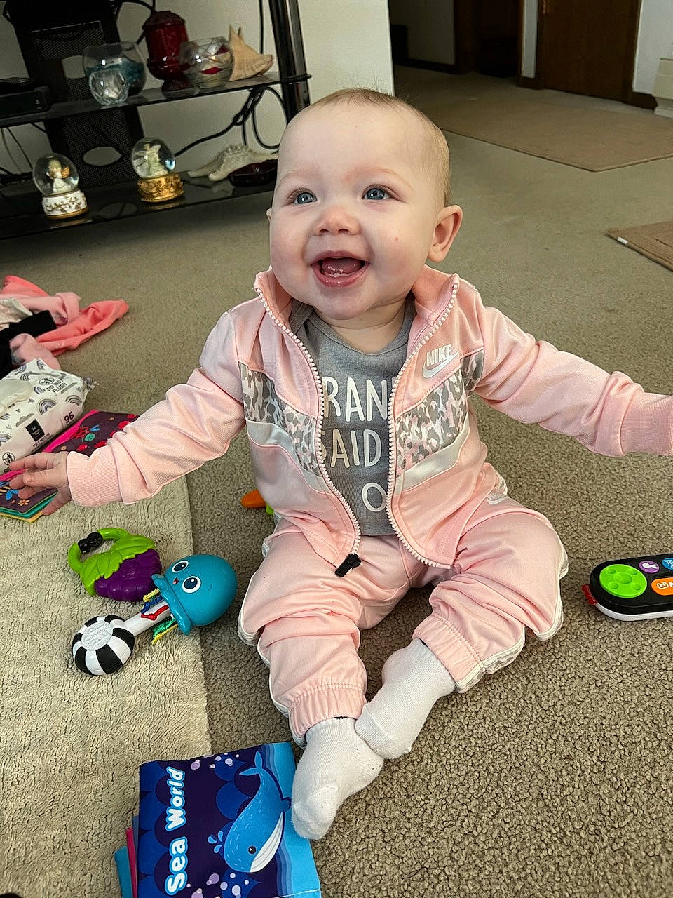 Alaina is registered to the contest to win money with this photo: baby, baby_toddler_clothing, baby_toys, carmine, cheek, child, cool, facial_expression, flooring, fun, happy, joint, person, play, sitting, skin, sleeve, smile, t_shirt, toddler