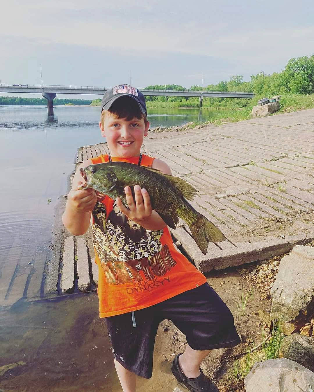 Camden is registered to the contest to win money with this photo: cloud, fish, fisherman, fun, happy, hat, joy, lake, landscape, leisure, person, plant, recreation, shorts, sky, sleeve, smile, soil, t_shirt, tourism