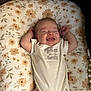 Heidi is registered to the contest to win money with this photo: baby, infant, smiling, onesie, floral_pattern, cushion, lying_down, happy, cute, tongue_out, arms_up, child, soft_lighting, indoors, peaceful, comfort, young, sleepy, adorable, person