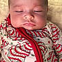 baby, sleeping, close_up, face, onesie, clothing, red, green, pattern, holiday, festive, infant, soft_skin, peaceful, cute, portrait, child, indoors, newborn, relaxed