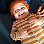 Jaxon is registered to the contest to win money with this photo: apparel, baby, blanket, child, cozy, cute, face, hands, happy, hat, indoor, infant, knit_hat, lying_down, onesie, person, portrait, smiling, striped_clothing, warm_lighting
