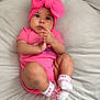 Evangelinne is registered to the contest to win money with this photo: baby, infant, pink_clothing, headband, bow, socks, cushion, soft_furniture, indoors, cute, portrait, child, person, relaxed, comfortable, curious, small_hands, big_eyes, cozy, casual