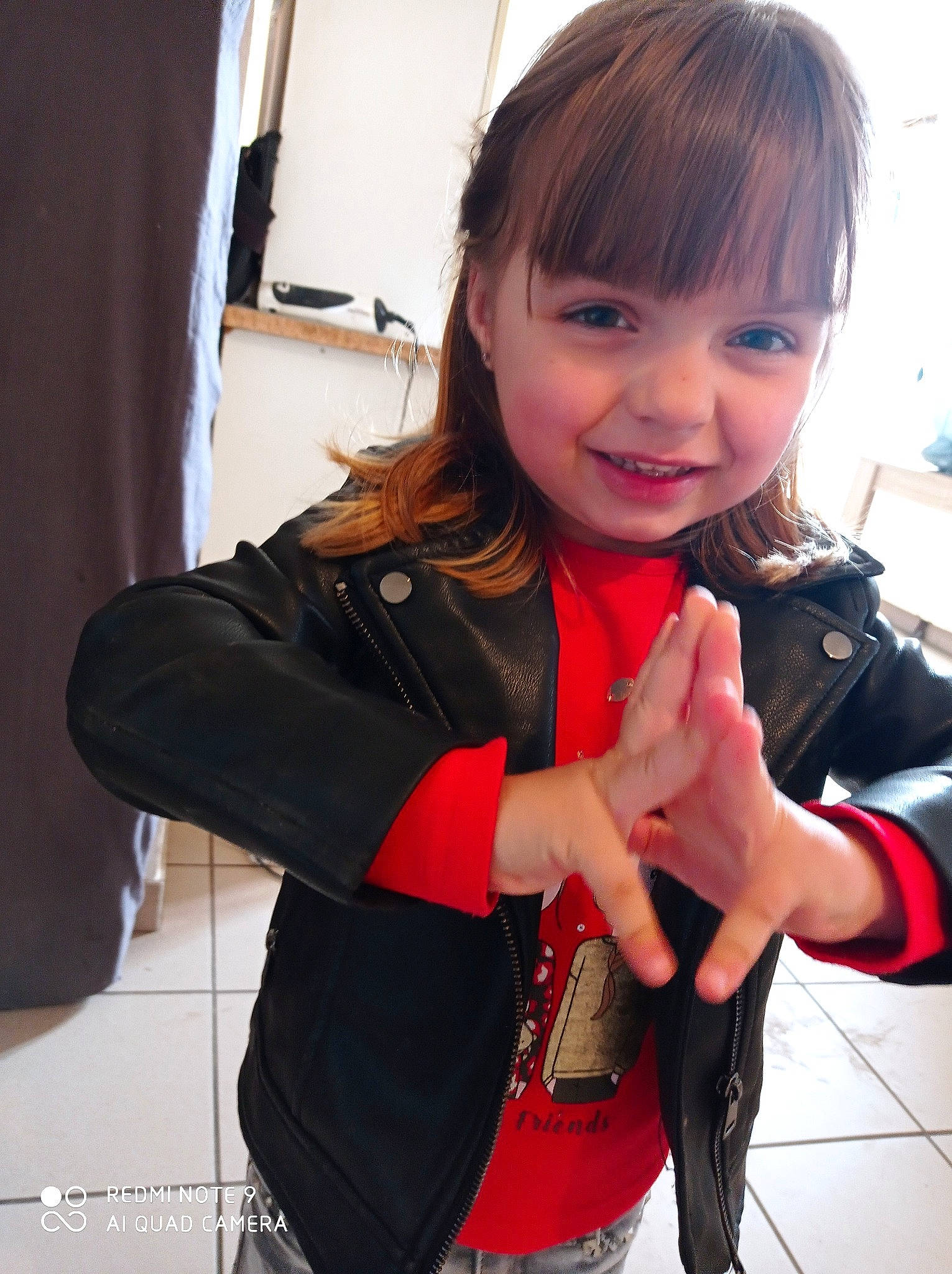 Tess participe au concours pour gagner de l'argent avec cette photo : bangs, black_hair, brown_hair, curtain, fun, gesture, glove, happy, human_leg, joy, lip, long_hair, nail, person, personal_protective_equipment, skin, sleeve, smile, street_fashion, thigh