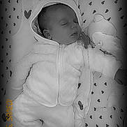 Oria a rejoint le concours — aidez-le/la à gagner de superbes lots ! baby, infant, sleeping, hooded_jacket, onesie, closed_eyes, pacifier_clip, plush_toy, heart_pattern, blanket, crib, soft_fabric, cozy, monochrome, portrait, hand, head, cheek, zipper, bedding