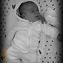 baby, infant, sleeping, hooded_jacket, onesie, closed_eyes, pacifier_clip, plush_toy, heart_pattern, blanket, crib, soft_fabric, cozy, monochrome, portrait, hand, head, cheek, zipper, bedding