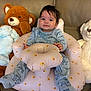 baby, infant, plush_toy, stuffed_animal, bear, bunny, seat, inflatable_seat, couch, smiling, blue_onesie, animal_print, child, indoors, soft_toys, cute, comfortable, happy, toddler, hair