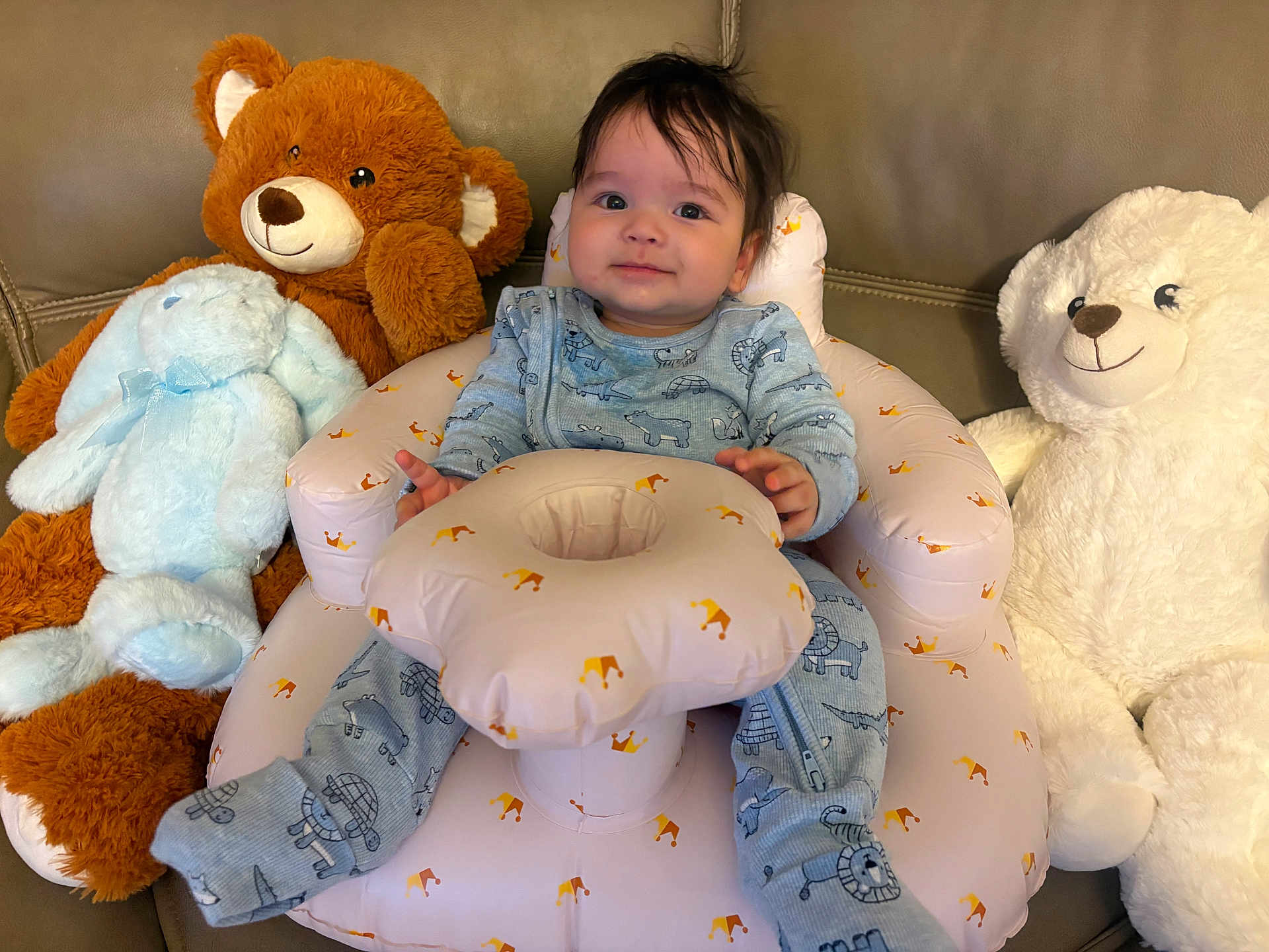 Ike is registered to the contest to win money with this photo: baby, infant, plush_toy, stuffed_animal, bear, bunny, seat, inflatable_seat, couch, smiling, blue_onesie, animal_print, child, indoors, soft_toys, cute, comfortable, happy, toddler, hair