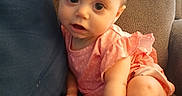 Aurora Luna is registered to the contest to win money with this photo: baby, child, bow, red_bow, pink_clothing, couch, blue_pillow, indoors, infant, cute, sitting, foot, hand, face, eyes, skin, furniture, expression, young_child, portrait