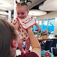 Aurora Luna joined the competition — help win amazing prizes! baby, child, person, adult, indoor, dining_room, table, chair, food, smile, happy, hair, pigtails, bib, clothing, window, light, modern, family, interaction