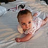 baby, child, toddler, bed, white_bedding, pink_scrunchie, pony_tail, infant_clothing, socks, cute, portrait, lying_down, indoors, soft_lighting, curious, small_hands, young_child, blanket, sleepwear, resting