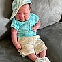 baby, infant, child, cap, hat, shorts, shirt, shoes, couch, furniture, indoors, cute, toddler, clothing, sitting, expression, skin, footwear, person, relaxing