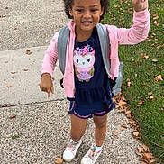 Aviana is registered to the contest to win money with this photo: child, girl, outdoor, sidewalk, grass, leaves, pink_jacket, blue_outfit, owl_graphic, white_sneakers, peace_sign, pointing, smiling, curly_hair, backpack, casual_clothing, fall, daytime, happy, playful