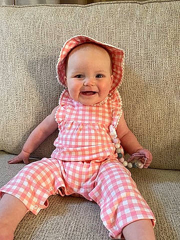 Devon is registered to the contest to win money with this photo: baby, baby_toddler_clothing, cheek, comfort, eye, face, happy, head, joy, linens, lip, pattern, person, pink, plaid, skin, sleeve, smile, t_shirt, tartan