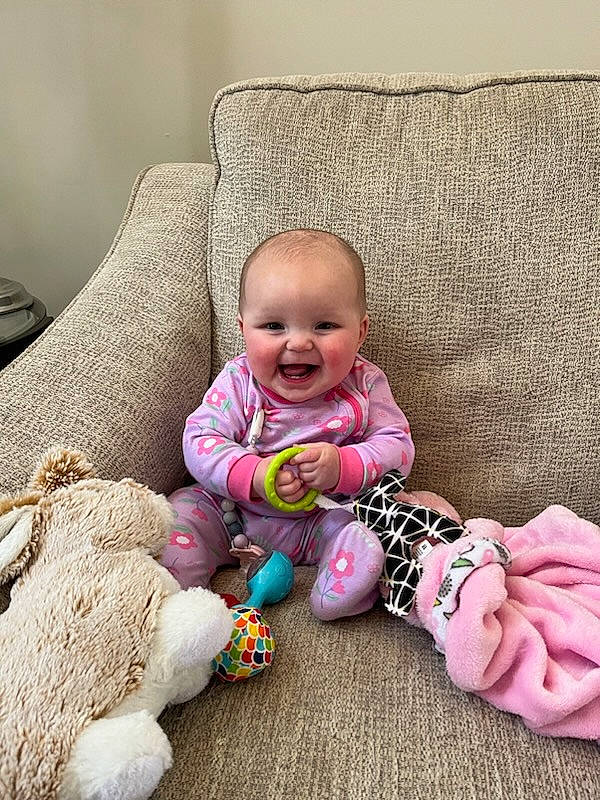 Devon is registered to the contest to win money with this photo: baby, baby_toddler_clothing, cheek, child, comfort, couch, flooring, grass, happy, head, headgear, joy, linens, person, pink, sitting, skin, smile, textile, toddler