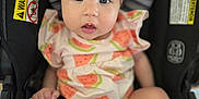 Evelyn is registered to the contest to win money with this photo: baby, infant, child, car_seat, headband, pink_bow, watermelon_pattern, clothing, face, eyes, legs, fingers, cute, expression, indoor, seatbelt, safety, portrait, person, young