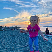 Liza joined the competition — help win amazing prizes! toddler, child, jumping, beach, sand, sunset, sky, clouds, smile, happy, person, log, water, shoreline, nature, outdoor, footwear, clothing, casual, recreation