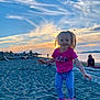 toddler, child, jumping, beach, sand, sunset, sky, clouds, smile, happy, person, log, water, shoreline, nature, outdoor, footwear, clothing, casual, recreation