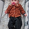 baby, baby_bed, child, childcare, clothing, corduroy_jacket, cute, cute_outfit, indoor, infant, lying_down, pacifier, pants, person, pink_pacifier, playpen, portrait, socks, soft_bedding, white_socks