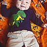 Karsyn joined the competition — help win amazing prizes! baby, child, infant, smiling, happy, portrait, lying_down, blanket, orange_blanket, dinosaur_shirt, t_rex, clothing, long_sleeves, pants, indoors, close_up, face, eyes, playful, cozy