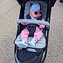 baby, stroller, sunglasses, headband, pink_clothing, sneakers, outdoor, child, footwear, pavement, seat, straps, sunshade, person, casual, accessory, walking_path, cute, infant, fashion