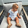baby, child, outdoor, chair, cushion, romper, sandals, curly_hair, skin, person, seated, fence, gravel, wood, footwear, expression, summer, casual, cute, infant