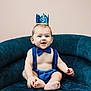 baby, blue, bow_tie, celebration, chair, child, clothing, crown, cute, happy, headwear, indoor, infant, person, plush, portrait, sitting, smile, suspenders, young