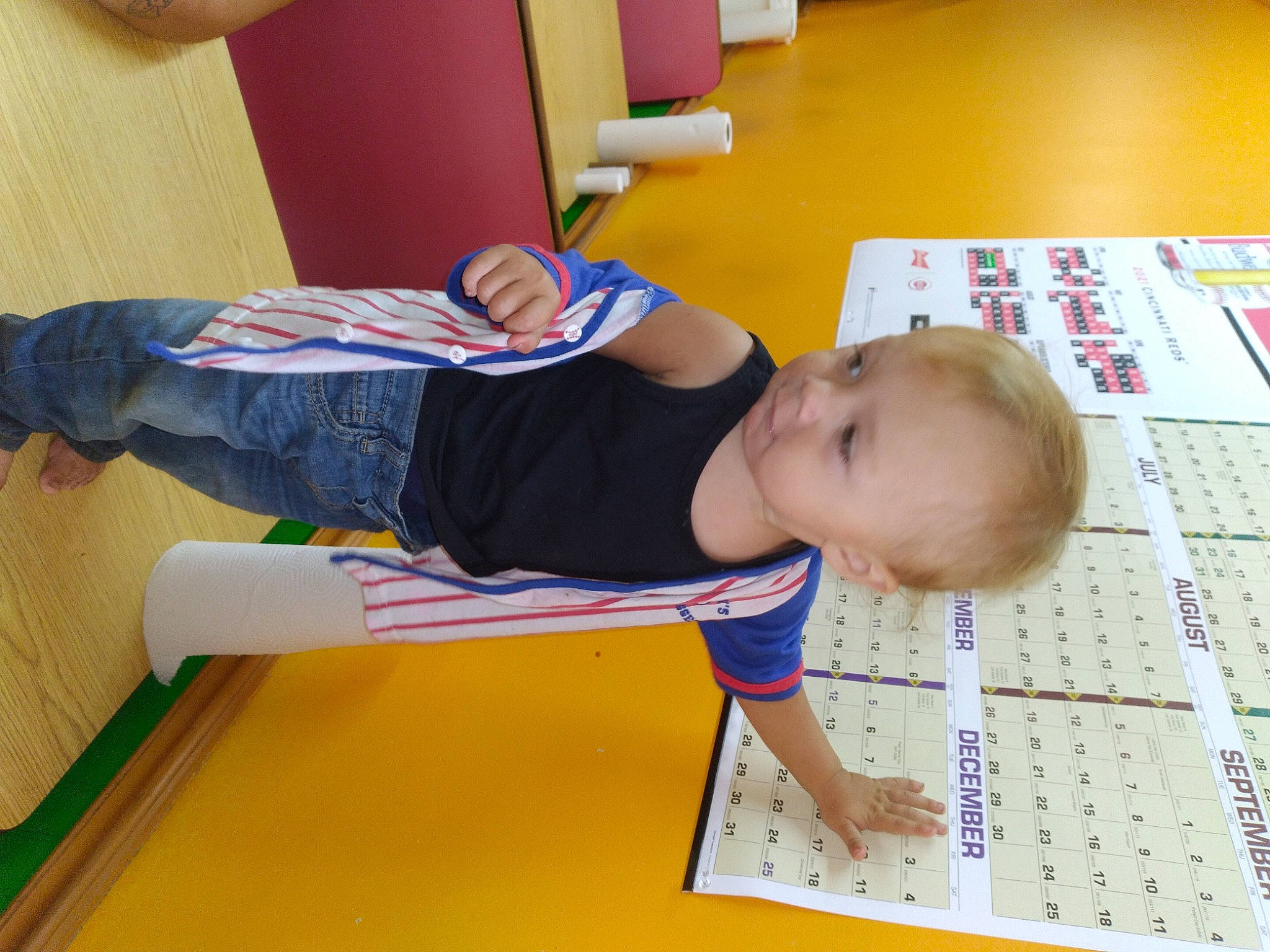 Roy is registered to the contest to win money with this photo: baby, baby_toddler_clothing, child, comfort, elbow, floor, flooring, fun, human_body, human_leg, knee, leisure, person, play, room, sitting, t_shirt, thigh, thumb, toddler