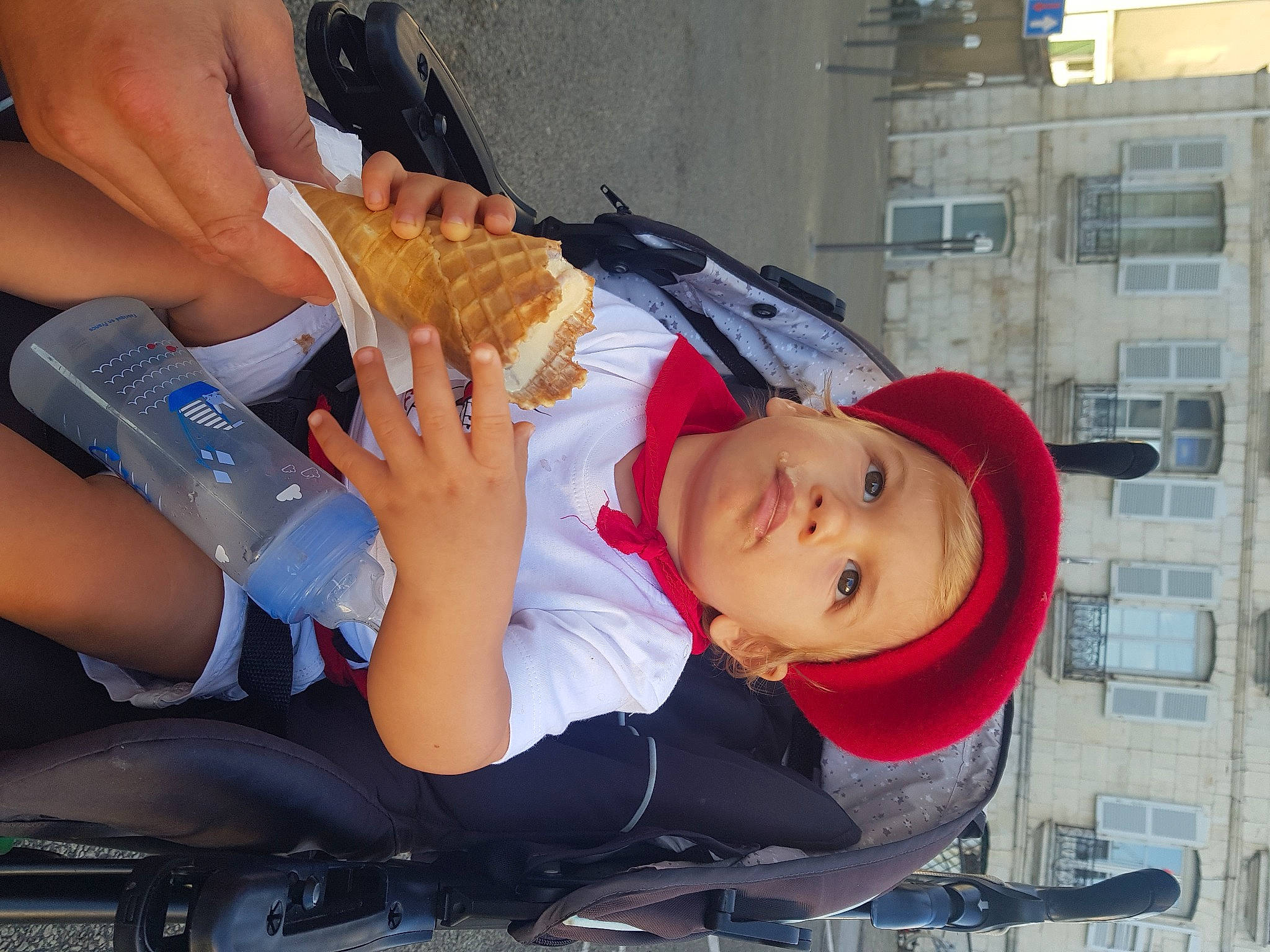 Louka participe au concours pour gagner de l'argent avec cette photo : baby, building, cap, child, elbow, food, fun, hat, headwear, hot_dog, human_leg, junk_food, mouth, nail, person, sitting, smile, sun_hat, thigh, toddler