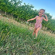 Alma participe au concours pour gagner de l'argent avec cette photo : blue_sky, child, daytime, field, grass, greenery, happy, nature, outdoor, person, pigtails, pink_romper, plants, playful, portrait, smiling, summer, sunny, toddler, wildflowers