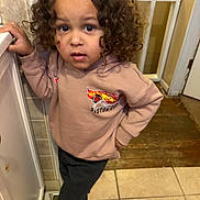 Carsen joined the competition — help win amazing prizes! child, toddler, curly_hair, brown_hair, portrait, standing, indoor, bathroom, sweatshirt, race_car, black_pants, shoes, tile_floor, wood_floor, door, mirror, hand_on_hip, serious_expression, blue_eyes, casual_clothing