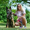 dog, woman, person, outdoor, grass, park, trees, nature, portrait, sitting, smiling, sunglasses, blonde_hair, tattoos, collar, leash, german_shepherd, animal, daylight, pet