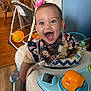 baby, child, walker, toy, smiling, happy, indoor, person, headband, flower, clothing, hand, blue, orange, furniture, floor, wood, bandana, cheerful, portrait