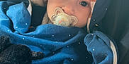 Milo participe au concours pour gagner de l'argent avec cette photo : baby, pacifier, blue_clothing, hood, polka_dots, plush_toy, car_seat, child, infant, cute, soft_toy, cozy, wrapped, young_child, portrait, indoors, seatbelt, face, looking, adorable