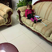 Bella joined the competition — help win amazing prizes! child, girl, sofa, living_room, plant, furniture, floor, tile, wood, clothing, pink_sweater, black_skirt, purple_tights, remote_control, indoor, home, seat, pensive, decor, toy