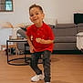 boy, casual_clothing, child, coffee_table, cookie, cushion, furniture, happy, home, indoor, living_room, mirror, plant, red_shirt, ripped_jeans, smiling, sofa, vase, white_sneakers, wooden_floor